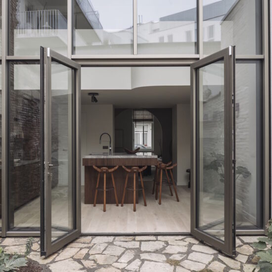 Het gebouw heeft een hoge aluminium gevelraam dat opvallend is door zijn bruin-grijze kleur en goudgrijze anodiseerafwerking. De Reynaers aluminium profielen zorgen voor strakke lijnen en een moderne uitstraling. Het grote gevelraam laat een overvloed aan lichtinval toe, wat bijdraagt aan de open en lichte sfeer van de architectuur. De moderne architectuur wordt benadrukt door de strakke, minimalistische vormgeving en de hoogwaardige afwerking van de aluminium profielen. Het geheel straalt een eigentijdse en stijlvolle uitstraling uit. Moderne keuken interieur met aluminium gevelraam